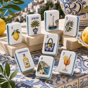 May include: A set of white rectangular game tiles featuring colorful illustrations including a lemon, a potted citrus tree labeled JOKER, a sailboat, an olive branch, a tote bag, a limoncello bottle, a coastal landscape, and a cocktail.