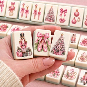 May include: A set of off-white mahjong tiles featuring festive Christmas illustrations in shades of pink and green. The tiles display detailed graphics of a nutcracker, ballet slippers with a large pink bow, and a decorated Christmas tree with gifts.