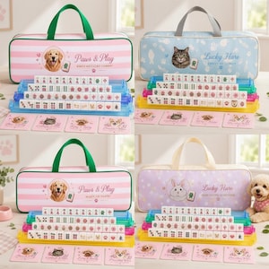 May include: Four sets of mahjong tiles arranged on tiered racks with matching carrying cases. The cases feature animal illustrations, stripes or polka dots, and text including Paws & Play or Lucky Hare. Each set includes four small square cards.