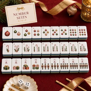 K&ouml;nnte beinhalten: Ein Mahjong-Spielset mit weihnachtlichen Illustrationen wie Christbaumkugeln, Zuckerstangen, Geschenken und Nussknackern. Die Spielsteine sind in drei Reihen angeordnet, erg&auml;nzt durch eine Karte mit der Aufschrift NUMBER SUITS und zwei wei&szlig;e W&uuml;rfel.