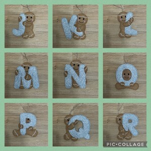 May include: Nine felt ornaments shaped like letters of the alphabet, J, K, L, M, N, O, P, Q, and R. Each letter is decorated with silver glitter and a gingerbread man holding the letter.