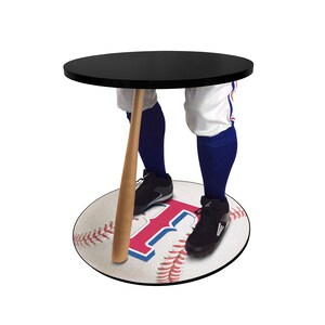 May include: A black round table with a baseball bat as the leg. The table top is black and the base is a white baseball with red stitching and a red "R" in the center. The table is about 2 feet tall.