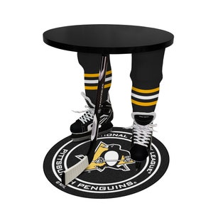 Peut inclure: Table de hockeyeur noir et or avec un plateau rond noir et un bâton de hockey entre les jambes. La table est sur un tapis noir et or des Penguins de Pittsburgh.