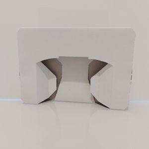 Puede incluir: Caja de cartón blanca con dos secciones recortadas, diseñada para contener dos artículos, como tazas o vasos.