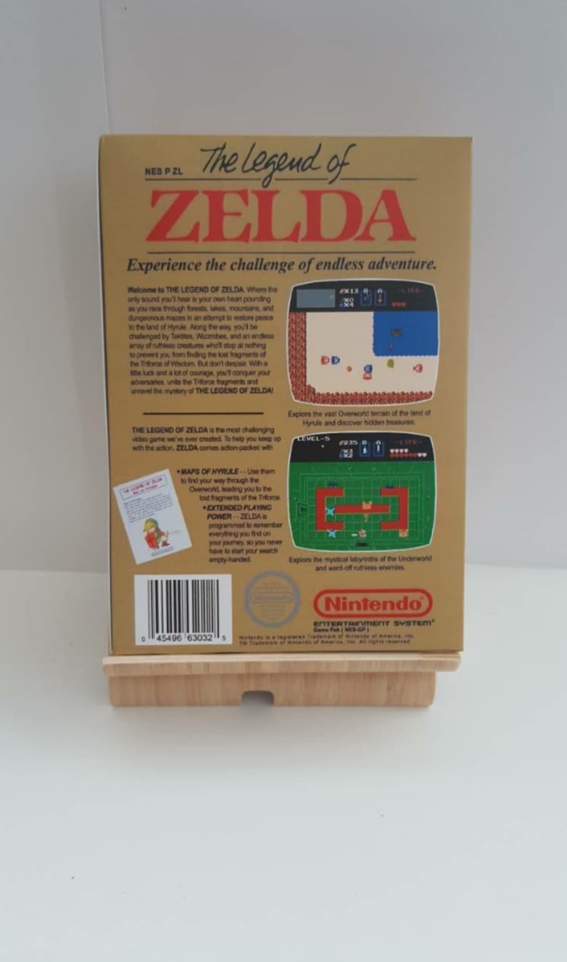 Może przedstawiać: Kaseta z grą The Legend of Zelda do systemu rozrywki Nintendo. Tył pudełka przedstawia złote tło z opisem gry i zrzutami ekranu. Gra jest opisana jako wymagająca przygoda z mapami, rozszerzoną mocą gry i r&oacute;żnymi wrogami.
