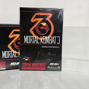 Könnte beinhalten: Eine schwarze Super Nintendo-Spielkassette mit einem roten und gelben Mortal Kombat 3-Logo. Die Hülle ist mit "PAL Version" beschriftet. Das Handbuch ist ebenfalls abgebildet, mit schwarzem Hintergrund und einem roten und gelben Mortal Kombat 3-Logo.