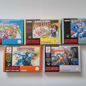 Könnte beinhalten: Fünf Super Nintendo-Spielkassetten, darunter Super Mario Kart, Super Mario All-Stars, Mega Man X, Sunset Riders und Castlevania IV. Die Kassetten sind in einer Reihe auf einer weißen Oberfläche angeordnet.