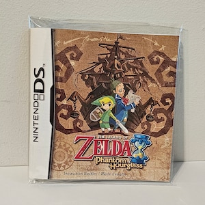 Puede incluir: El folleto de instrucciones de The Legend of Zelda: Phantom Hourglass para Nintendo DS. La portada muestra a Link y un personaje pirata de pie frente a un barco.