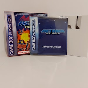 Puede incluir: Una caja de juego Game Boy Advance blanca con un folleto de instrucciones azul y blanco. La caja tiene una imagen de un personaje del juego Metroid Zero Mission en la parte delantera. El texto "GAME BOY ADVANCE" está impreso en el lateral de la caja.