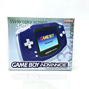 Könnte beinhalten: Eine verpackte Game Boy Advance Handheld-Konsole. Die Box zeigt eine blaue Konsolengrafik mit dem Text "GAME BOY ADVANCE" und "Wide color screen 32bit". Das Nintendo-Logo ist sichtbar.