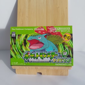 May include: A green and yellow Game Boy Advance video game cartridge for Pokemon LeafGreen. The cartridge features a cartoon image of a green and blue Pokemon character with red eyes. The text on the cartridge reads "Pokemon LeafGreen" and "Game Boy Advance".