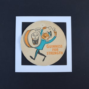 May include: Vintage Guinness beer coaster featuring a cartoon character carrying a barrel of Guinness. The character is dressed in blue and orange, with the words "Guinness for Strength" printed in orange.