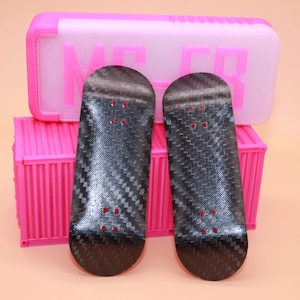 以下が含まれることがあります： カーボンファイバー模様の黒いフィンガーボードが2つ。フィンガーボードはピンクのコンテナの上に置かれています。