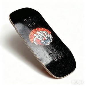 Puede incluir: Fingerboard negro con un gráfico que presenta una mano esquelética sosteniendo un monopatín. El gráfico es rojo, blanco y azul. El fingerboard tiene agujeros pre-perforados para montar los ejes.