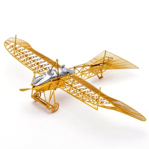 May include: A gold metal model of a vintage airplane with a silver propeller and a detailed wire frame design.
