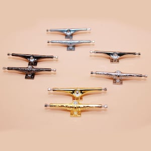 Peut inclure: Ensemble de huit trucks de skateboard en quatre couleurs différentes : argent, noir, or et argent brossé. Les trucks sont conçus pour les fingerboards et ont un look classique.