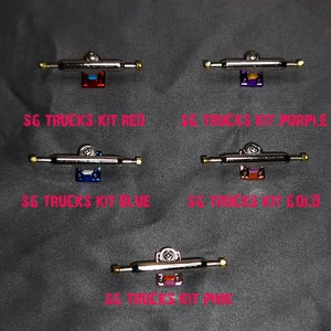 May include: Four sets of fingerboard trucks in different colors. The trucks are silver with gold accents. The trucks are labeled "SG Trucks Kit Red", "SG Trucks Kit Purple", "SG Trucks Kit Blue", and "SG Trucks Kit Gold".