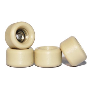 Puede incluir: Cuatro ruedas de fingerboard de color blanco roto. Las ruedas son de plástico liso y duro y tienen un perfil ligeramente redondeado.