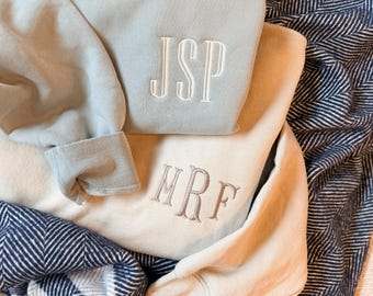 Può includere: Due felpe a girocollo, una in verde salvia chiaro con lettere JSP ricamate in bianco e una color crema con lettere MRF ricamate in marrone chiaro. Entrambi i capi presentano maniche lunghe con polsini a coste e un tessuto a tinta unita.