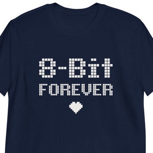Puede incluir: Camiseta azul marino con el texto "8-Bit Forever" en fuente pixelada. Un corazón pixelado está debajo del texto. La camiseta es de manga corta.