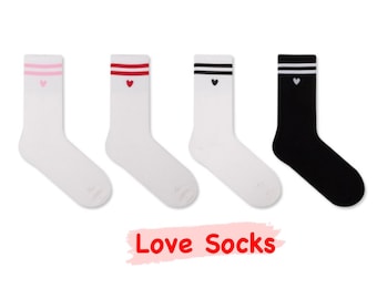 May include: Four pairs of white socks with red, pink, or black stripes and a small heart design. The socks have the text "Love Socks" printed on the bottom.