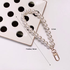 May include: A white pearl chain with a gold clasp. The chain is 7 inches or 18 cm long and the pearls are 1.2 cm in diameter.