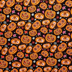 May include: A black fabric pattern featuring orange pumpkins decorated with sugar skull motifs, including floral eye sockets and stitched mouths, interspersed with small pink and white flowers and thin spider web lines across the dark background.