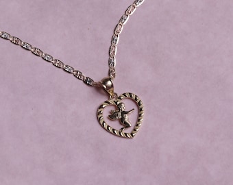 May include: A gold necklace with a heart-shaped pendant featuring a cherub inside. The chain is a delicate, two-tone design.
