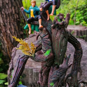 May include: A tree-like figure with a rough, brown bark texture and green moss accents. Two small figures, one in a green and blue outfit and the other in a brown and green outfit, are perched on the tree figure.