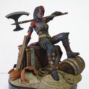 May include: A detailed figurine of a female warrior with red skin, horns, and a mohawk hairstyle. She is posed with an axe over her shoulder, wearing armor and seated on a wooden crate. A barrel and broken pottery are also present.