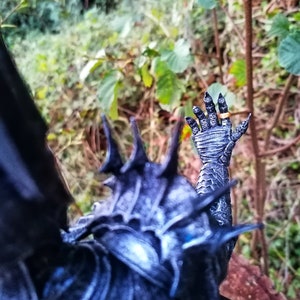 Op de afbeelding: Een zwart en zilveren action figure met een stekelig, gedetailleerd ontwerp. De figuur draagt een ring aan zijn vinger.