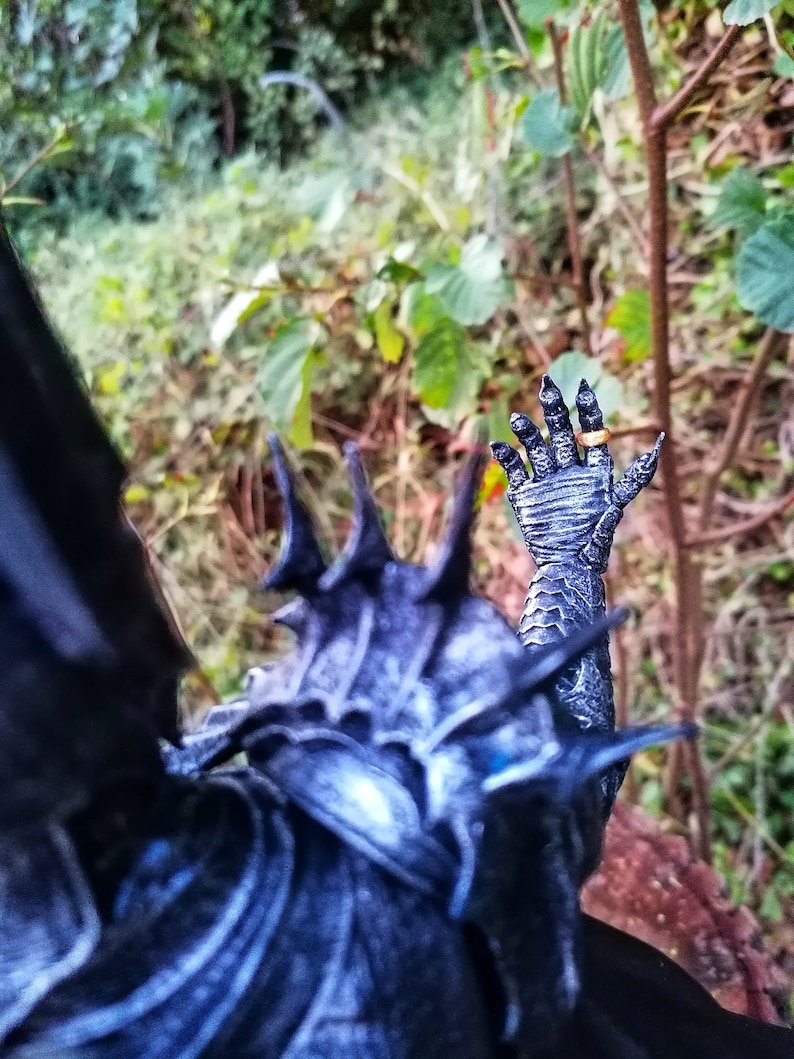 Op de afbeelding: Een zwart en zilveren action figure met een stekelig, gedetailleerd ontwerp. De figuur draagt een ring aan zijn vinger.