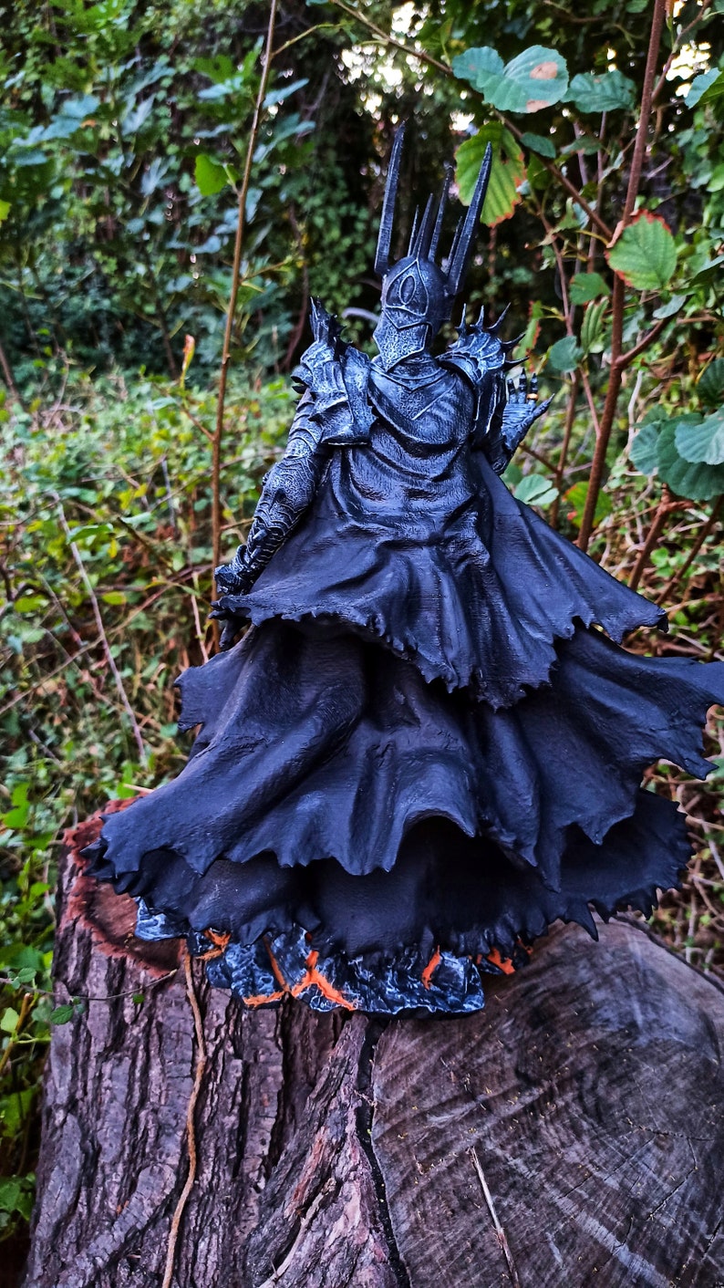 Op de afbeelding: Een zwart en zilveren beeldje van een duistere heer met een kroon en een vloeiende zwarte cape. Het beeldje staat op een boomstronk.