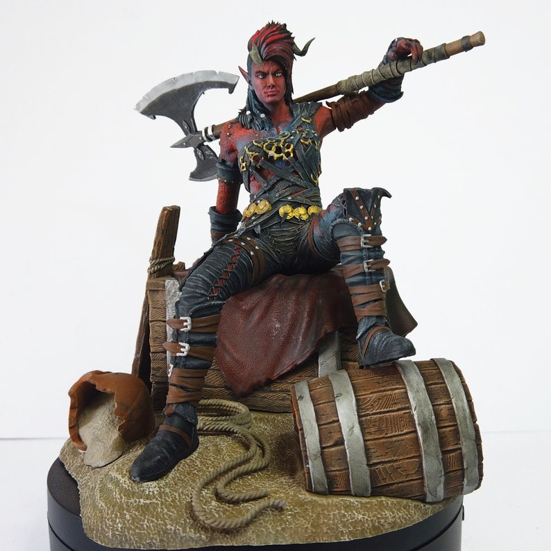 May include: A detailed figurine of a red-skinned character with horns, wearing dark armor and holding a large axe and staff. The figure is seated on a wooden barrel and platform, with a rope and other props.