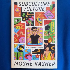 以下が含まれることがあります： Moshe Kasher著の書籍「Subculture Vulture: A Memoir in Six Scenes」。白い表紙には、複数の腕を持つ人物、マイク、レコード、そして鮮やかな色使いの様々な抽象的な形が描かれた、カラフルでセグメント化されたイラストがデザインされています。