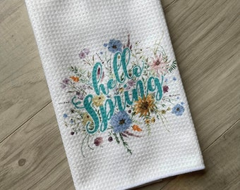 May include: White kitchen towel with a floral design and the text "hello spring" in teal.