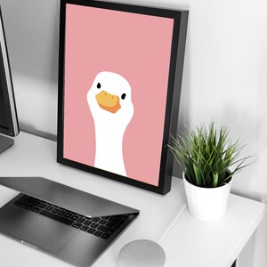 Puede incluir: Una impresi&oacute;n enmarcada de un ganso blanco con un pico naranja sobre un fondo rosa.