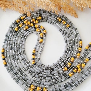 May include: A beaded waist chain with multiple strands of gray and black beads, accented with yellow beads.