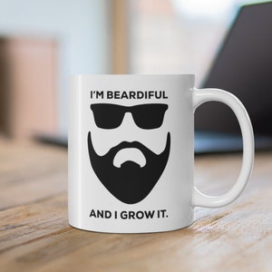 May include: White ceramic mug featuring a black and white illustration of a man with a beard and sunglasses. The text "I'm Beardiful and I Grow It." is printed on the mug.