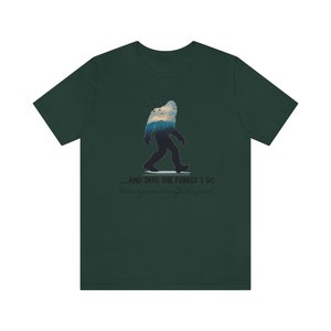 Peut inclure: Un t-shirt vert fonc&eacute; avec une silhouette de Bigfoot marchant dans une for&ecirc;t. Le texte sur le t-shirt est "...and into the forest I go to lose my mind and find my soul."