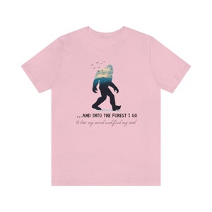 Peut inclure: T-shirt rose avec une silhouette de Bigfoot marchant dans une for&ecirc;t. Le texte dit "...AND INTO THE FOREST I GO to lose my mind and find my soul."