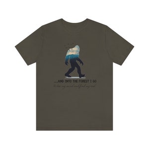 Peut inclure: Un t-shirt vert fonc&eacute; avec une silhouette de Bigfoot marchant dans une for&ecirc;t. Le texte sur le t-shirt est "...AND INTO THE FOREST I GO to lose my mind and find my soul."