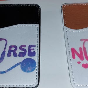 May include: Two white card holders with a pocket for a card. One card holder has a black leather exterior and the other has a brown leather exterior. Both card holders have the word "NURSE" printed on them in pink and white with a stethoscope graphic.