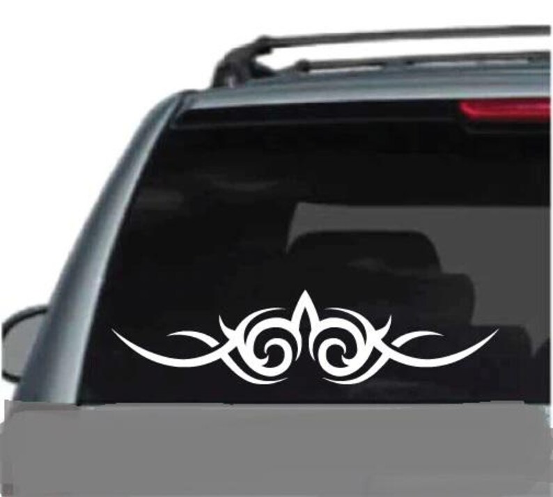 K&ouml;nnte beinhalten: Wei&szlig;es Tribal-Design-Autoaufkleber. Der Aufkleber hat ein symmetrisches Muster mit geschwungenen Linien und Wirbelelementen, geeignet f&uuml;r die Anbringung an der Heckscheibe oder Karosserie eines Fahrzeugs.