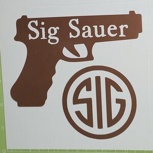 K&ouml;nnte beinhalten: Ein brauner Aufkleber mit einer Pistollensilhouette und den wei&szlig;en Worten "Sig Sauer". Unter der Pistole befindet sich ein braunes rundes Emblem mit den wei&szlig;en Buchstaben "SIG". Der Aufkleber befindet sich auf wei&szlig;em Hintergrund.