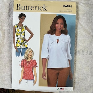 May include: A Butterick sewing pattern envelope featuring illustrations of women's tops. The pattern includes designs for a sleeveless top with a lemon print, a red floral top, and a white blouse with a keyhole neckline. The envelope has the number B6876.