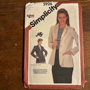 Puede incluir: Patrón de costura Simplicity número 5926 para una chaqueta beige con un logotipo de Jiffy. El patrón es para las tallas 6, 8 y 10. El patrón incluye instrucciones para hacer una chaqueta con un cierre de botón único y bolsillos. El patrón también incluye una imagen de una mujer usando la chaqueta.