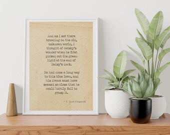 May include: A framed print of a vintage typewriter quote from F. Scott Fitzgerald's The Great Gatsby. The quote reads: "And as I sat there brooding on the old, unknown world, I thought of Gatsby's wonder when he first picked out the green light at the end of Daisy's dock. He had come a long way to this blue lawn, and his dream must have seemed so close that he could hardly fail to grasp it."