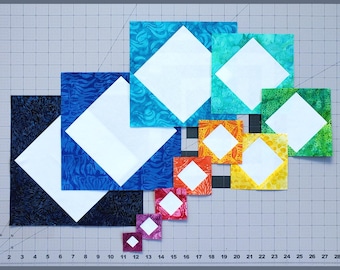 May include: A collection of ten square quilt blocks arranged in a diagonal gradient from dark blue to purple. Each block features a white square centered within a patterned fabric border, ranging in size from large to small, displayed on a grid mat.