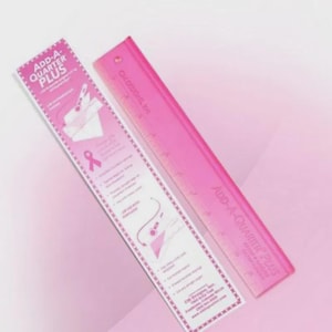 May include: Two pink rulers, one with the text "ADD-A-QUARTER PLUS" and a pink ribbon graphic. The other ruler is transparent pink with the text "ADD-A-QUARTER PLUS" and measurement markings. Both rulers are on a pink background.
